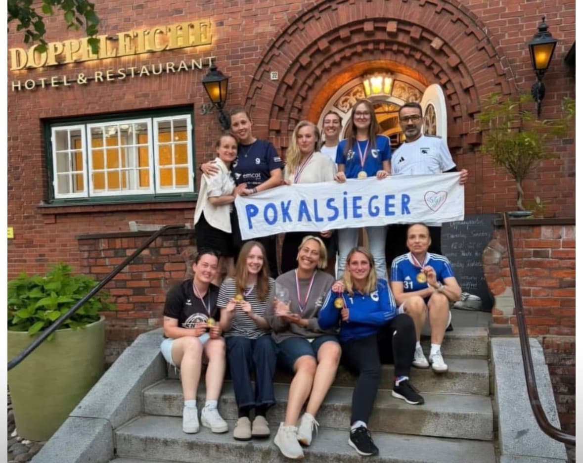 Die Fußball-Damen mit Medaillen und Pokalsieger-Banner auf der Treppe vor dem Hotel Doppeleiche